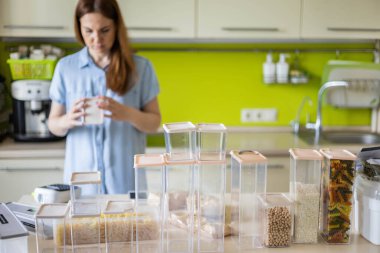 Mutfakta makarna depolamak için plastik kutuları işaretleyen odaklanmış kadın profesyonel uzay düzenleyici