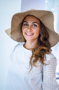 Moda şapkası takan, neşeli, genç, esmer, alışverişkolik bir kadın.