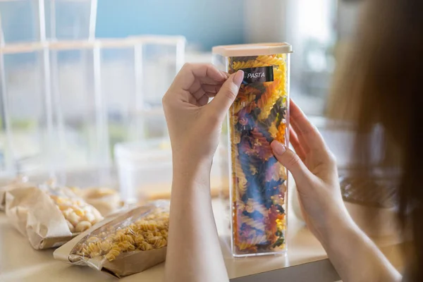 Primo piano mani femminili attaccare etichetta sulla pasta confezione di plastica. Organizzazione di magazzinaggio dei prodotti alimentari — Foto Stock