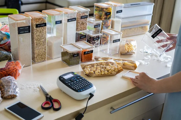 Top view woman hands sticking label marker on transparent plastic box with pasta