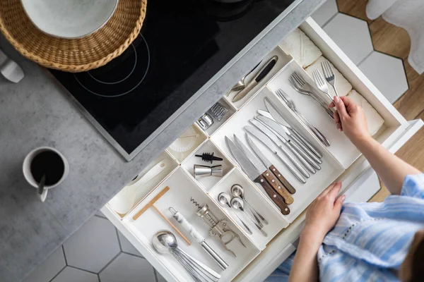 Vista superior primer plano ama de casa manos ordenar los cubiertos en el cajón de limpieza general en la cocina —  Fotos de Stock