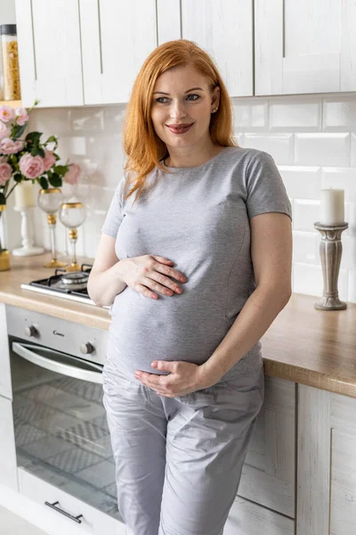 Happy pregnant woman posing with coffee tea mug in modern minimalistic nordic kitchen at home — Foto Stock