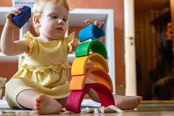 小女孩穿着连衣裙堆砌彩虹拱顶建筑生态木制玩具塔 — 图库照片