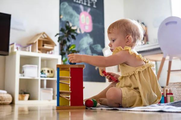 Bébé fille heureuse frappant marteau en bois sur des boules colorées développement précoce jouet écologique — Photo