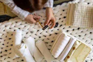 Kapalı ev kadını etiketleri kesiyor. Yastık kılıfı ve havlu deposu kullanımı Marie Kondo metodu.