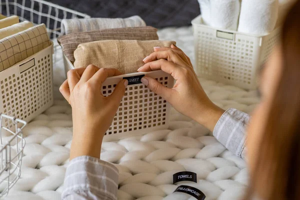 Las manos de mujer ropa de cama y toallas cuidadosamente dobladas utilizan el método Marie Kondo con etiquetas adhesivas —  Fotos de Stock