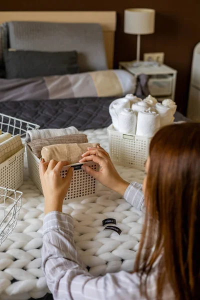 Vrouw handen netjes gevouwen linnengoed en handdoeken gebruik Marie Kondo methode met kleverige label tags — Stockfoto