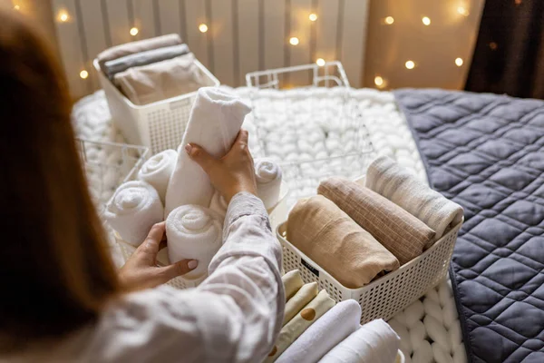 Ama de casa moderna poniendo toallas cuidadosamente dobladas, fundas de almohada, fundas nórdicas en una caja metálica de plástico —  Fotos de Stock