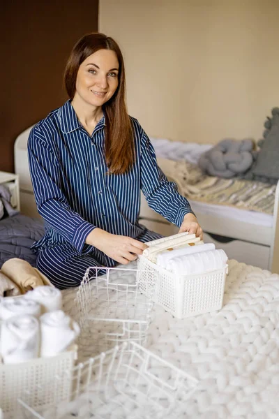 Modern housewife putting neatly folded towels, pillowcases, duvet covers into plastic metallic case