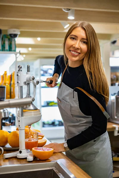 Retrato mujer sonriente camarera en delantal cocina desintoxicación saludable zumo refrescante pomelos de naranja —  Fotos de Stock