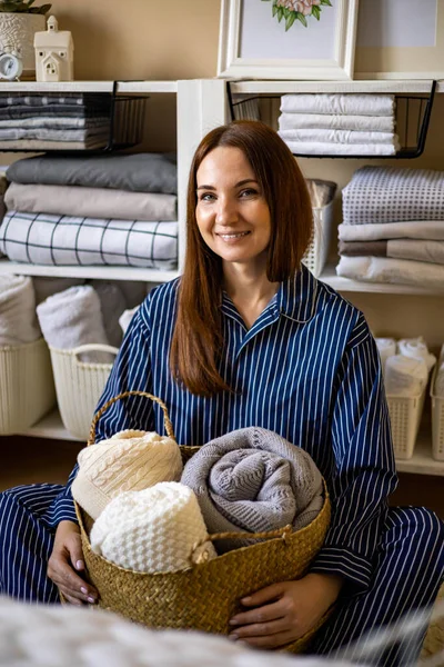 Retrato de mujer doméstica joven feliz en pijama posando con canasta de paja para el almacenamiento de ropa de cama —  Fotos de Stock