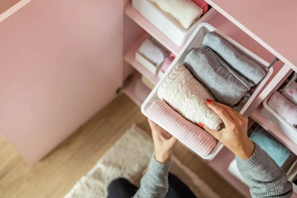 Счастливая молодая мама наслаждается уборкой в женском гардеробе аккуратно сложенной одежды — стоковое фото