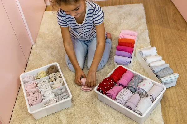 Feliz chica perfectamente rollo doblado ropa interior y calcetines en caja de plástico método Marie Kondo — Foto de Stock