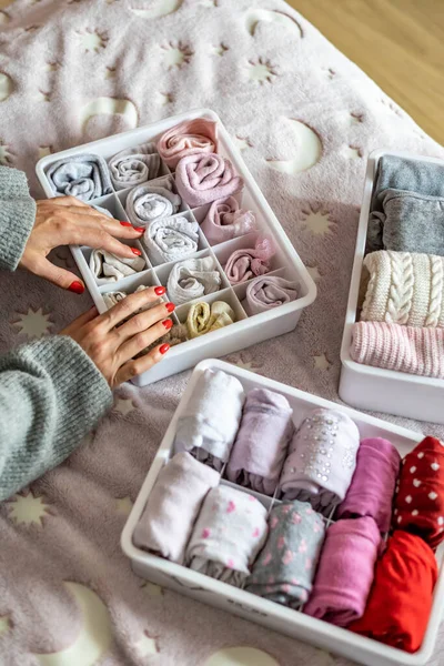 Üst düzey anne, kadın çocuk kıyafetlerini plastik kutu konforlu bir kutuya koyuyor.