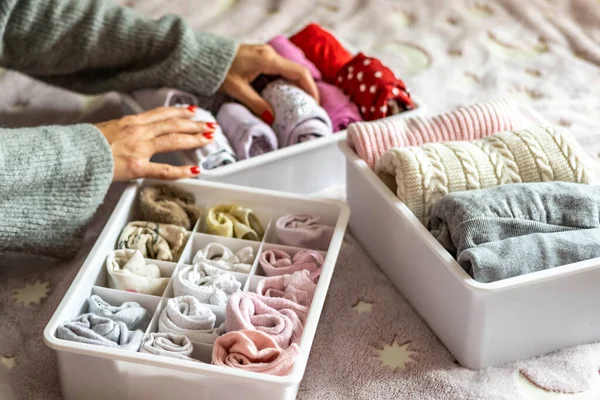 Üst düzey anne, kadın çocuk kıyafetlerini plastik kutu konforlu bir kutuya koyuyor.