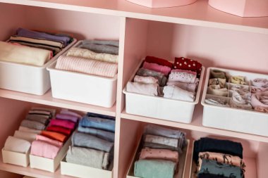Closeup shelves pink female childish closet with neatly folded clothes Marie Kondo vertical storage clipart