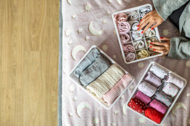 Üst düzey anne, kadın çocuk kıyafetlerini plastik kutu konforlu bir kutuya koyuyor.