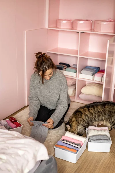 Mother and cat neatly folded daughter kid clothes in case box for comfortable vertical storage