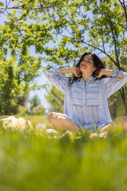 Nilüfer pozisyonunda oturan rahat kadın ekose üzerinde yaz bahçesindeki parkta sabah meditasyonunun keyfini çıkarıyor.