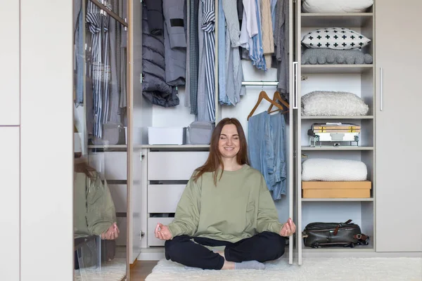 Mujer alegre en posición de loto en el armario de almacenamiento moderno. Feliz ama de casa posando meditando — Foto de Stock