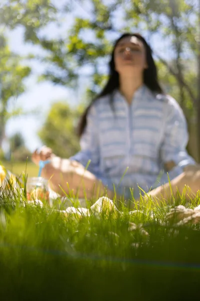 Pihent nő ül lótuszpozícióban kockás élvezi a reggeli meditáció a nyári kert parkban — Stock Fotó