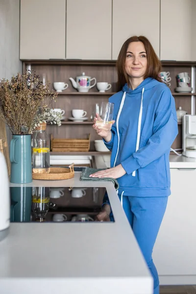 Szczęśliwa domowa kobieta pijąca detoks z cytryną w kuchni. Uśmiechnięta kobieta z napojem dietetycznym — Zdjęcie stockowe