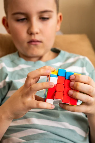 Сосредоточенный подросток собирает разноцветные куски кубика Рубика, наслаждаясь развитием разума — стоковое фото