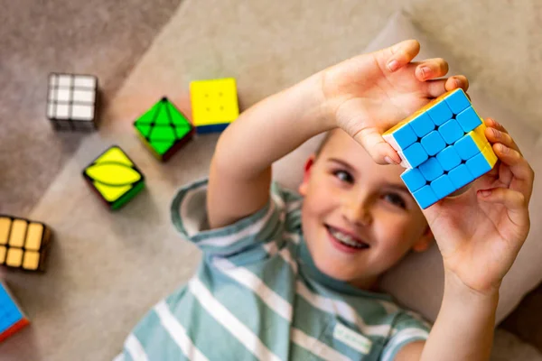 Вгорі - щаслива дитина, яка збирає багатоколірну розумову іграшку Рубікс куб з позитивними емоціями — стокове фото