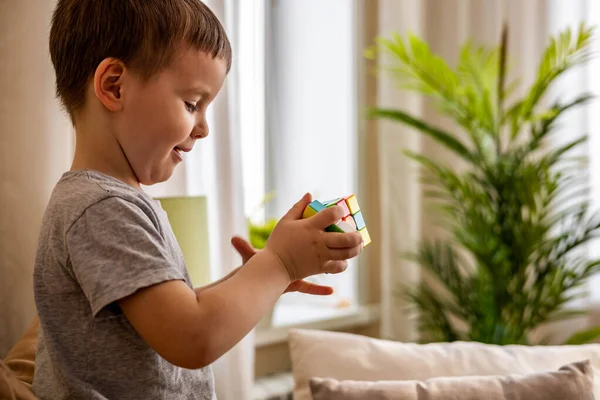 かわいいです赤ちゃん男の子アセンブリ多色rubiksキューブ解決論理ゲーム嘘オンソファにホーム — ストック写真
