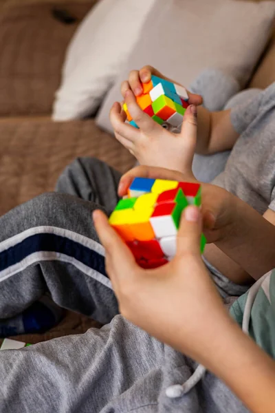 Одяг рук розумні діти збирають Rubiks куб 3x3 насолоджуючись раннім розробкою гри вдома — стокове фото