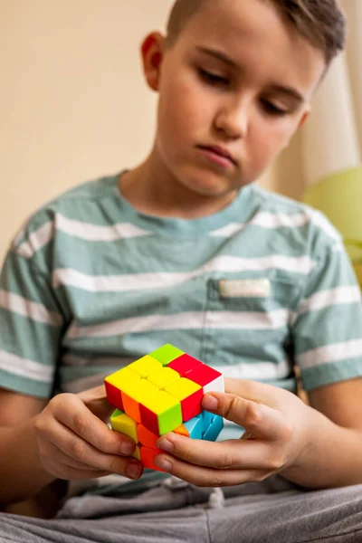 Зосереджений підліток збирає різнокольорові шматочки кубика Рубікса, насолоджуючись розумовим розвитком. — стокове фото
