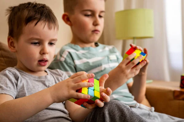 Two male kids brothers assembling Rubiks cube thinking solving logic decision — Stock Photo, Image