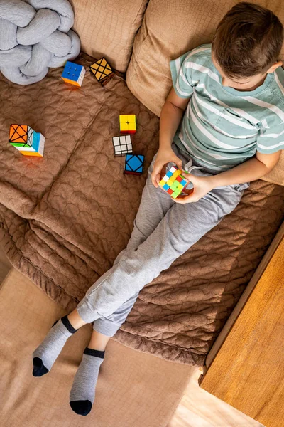 トップ表示男性子供組み立て多色Rubiksキューブ4 × 4リラックス座っています上のソファ — ストック写真