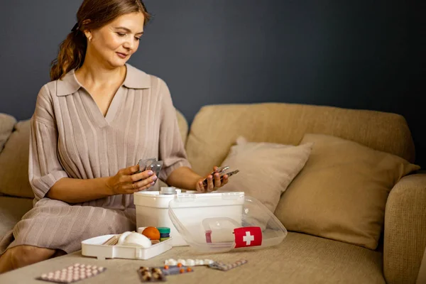 Female housewife checking medicines at domestic first aid kit neatly placing storage organization