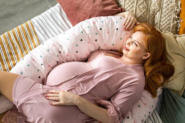 Вид зверху щаслива майбутня мати лежить на зручному ліжку обіймає подушку для вагітної розслабляючої Стокове Фото