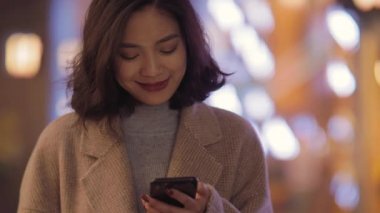 Kısa ve orta saçlı bir bayan tek eliyle cep telefonuyla oynuyordu.,