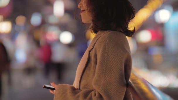 Bella donna cinese sta controllando il telefono nella notte rilassatamente. — Video Stock