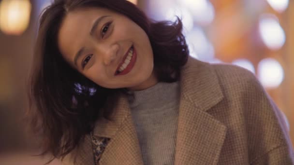 一个亚洲女孩把头歪着，嘴角挂着甜美的笑容. — 图库视频影像