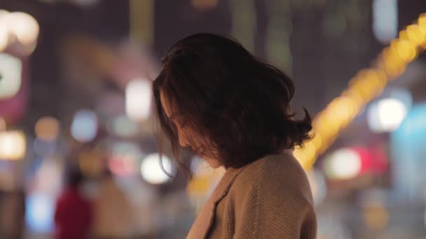 Jong aziatisch vrouw met behulp van mobiele telefoon in de stedelijke straat in de avond — Stockvideo