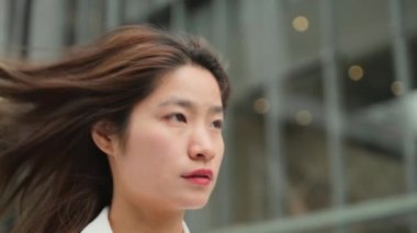 Beyaz takım elbiseli, kendine güvenen Asyalı iş kadını ofis binalarında dolanıyor iddialı kadın yavaş çekim klipsi