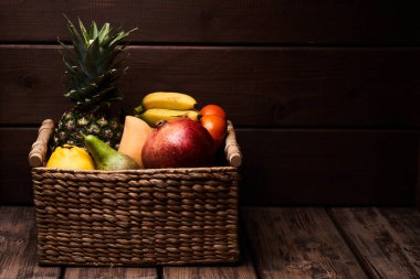 Tahta arka planda sepette taze renkli egzotik meyvelerin karışımı.