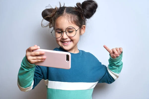 快乐可爱的小女孩被隔离在白色工作室的背景下 手里拿着手机 孩子们拿着智能手机笑着 — 图库照片