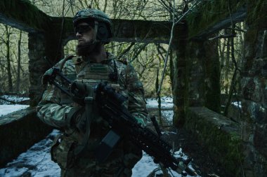 Ormanda makineli tüfekle profesyonel ekipman içinde uçan yumuşak oyuncunun portresi. Savaşta silahlı bir asker