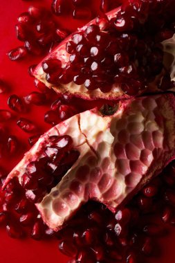 Kırmızı arka planda izole edilmiş taze, sulu, sulu, dilimlenmiş nar.