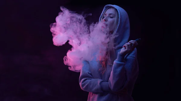 肖像画の美しいですブロンドの女の子でグレーパーカー煙蒸気煙の雲 黒のスタジオの背景に隔離されたVape — ストック写真