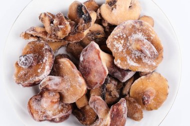 Donmuş mantarlar yakın plan beyaz tabakta izole edilmiş, kahverengi şampiyon pişirmeye hazır.