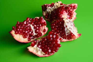 Olgun taze sulu dilimlenmiş yeşil arkaplanda izole edilmiş nar.