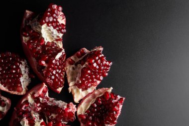 Siyah arka planda izole edilmiş kırmızı sulu dilimlenmiş nar.