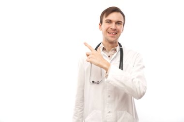 Steteskoplu beyaz önlüklü yakışıklı doktor beyaz arka planda izole edilmiş boş bir alanı işaret ediyor. Ürünü gösteriyor, heyecan verici bir şey gösteriyor.