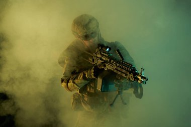 Terk edilmiş binada makineli tüfekle profesyonel ekipman içinde havalı oyuncunun portresi. Savaşta sisli ve dumanlı silahlı asker